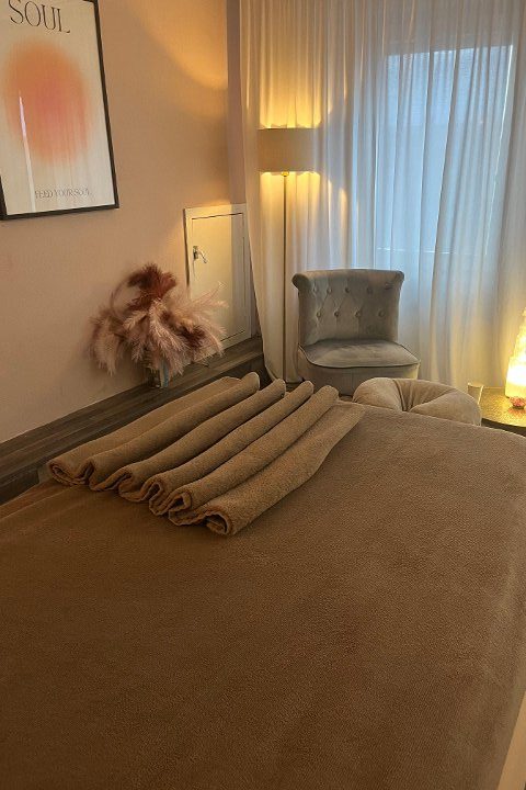 De behandelkamer van Wellness aan Zee met opgestapelde handdoeken en warm lamplicht